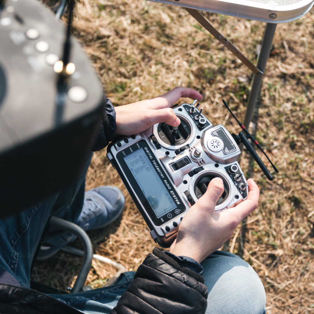Pessoa operando um drone FPV com um controle remoto digital em um campo aberto, ilustrando o uso de drones FPV no Brasil para entretenimento e produção audiovisual